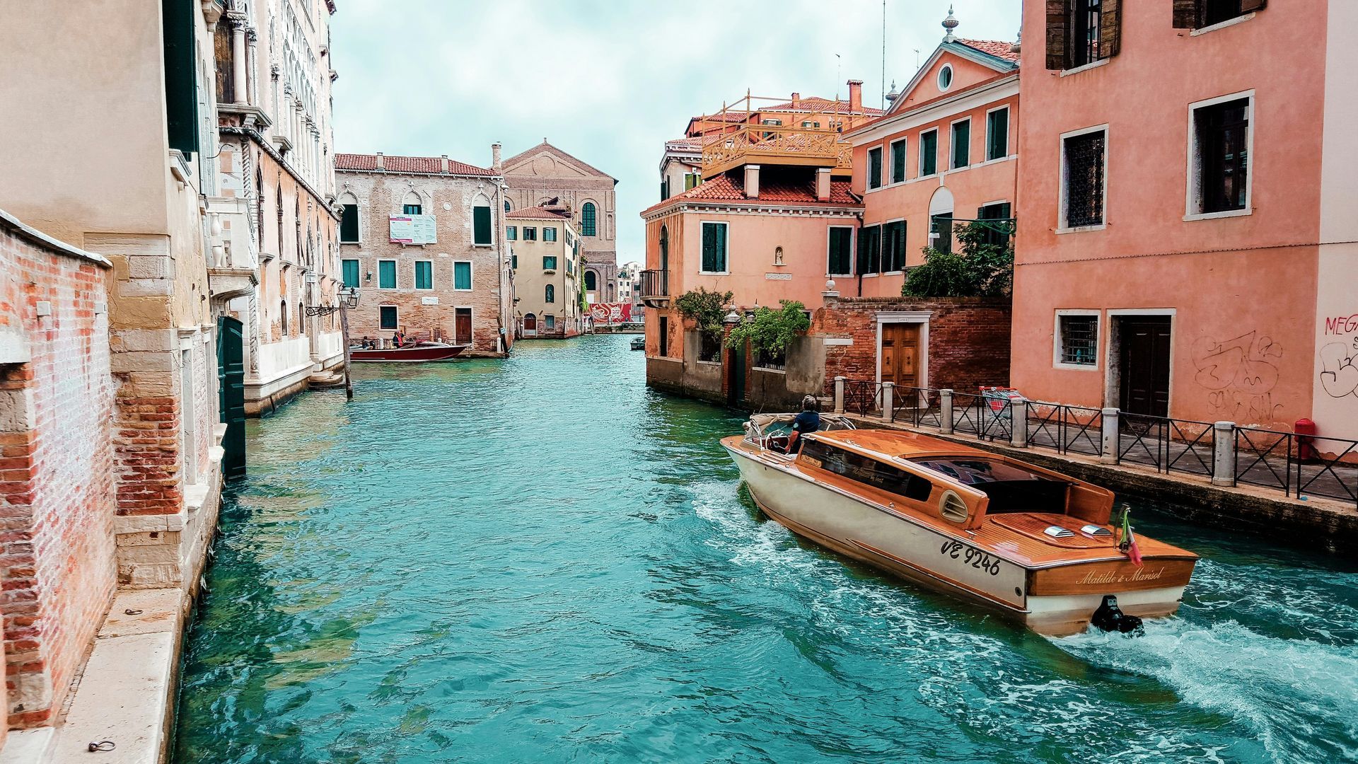 Venice canal with boat traveling between colorful buildings.