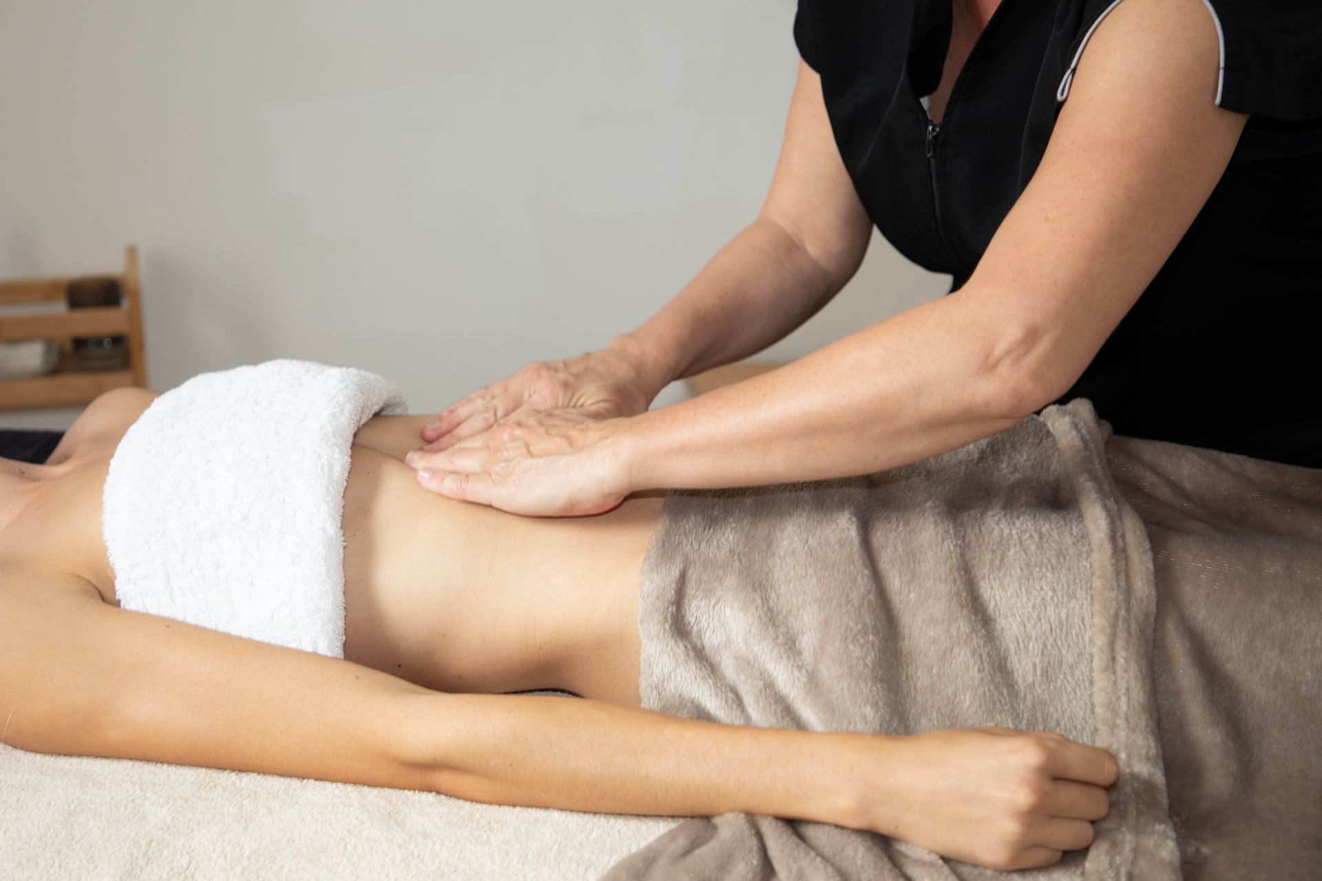 A woman is getting a massage on her stomach while wrapped in a towel.