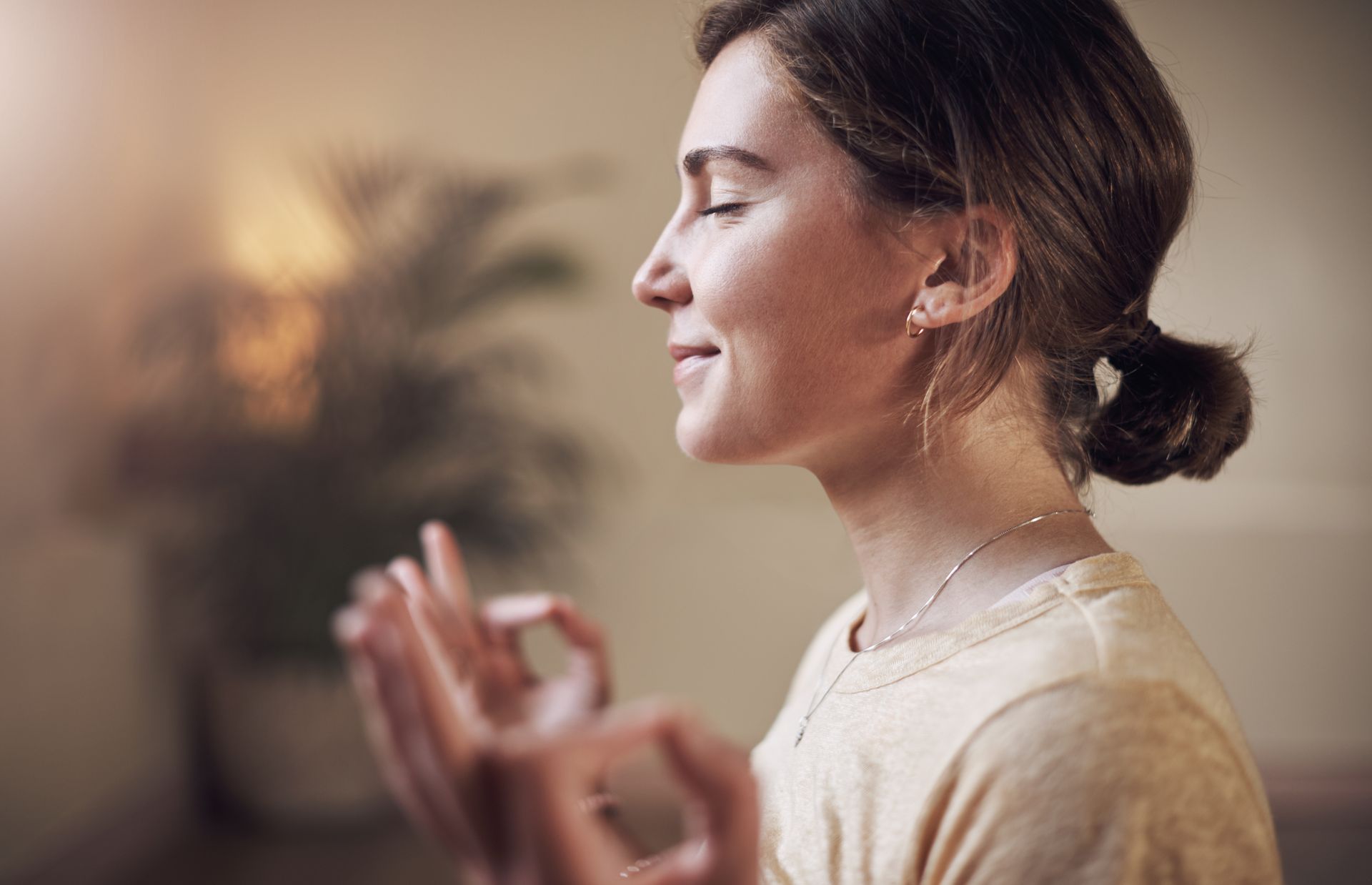 A woman is meditating with her eyes closed and her hands in a circle.