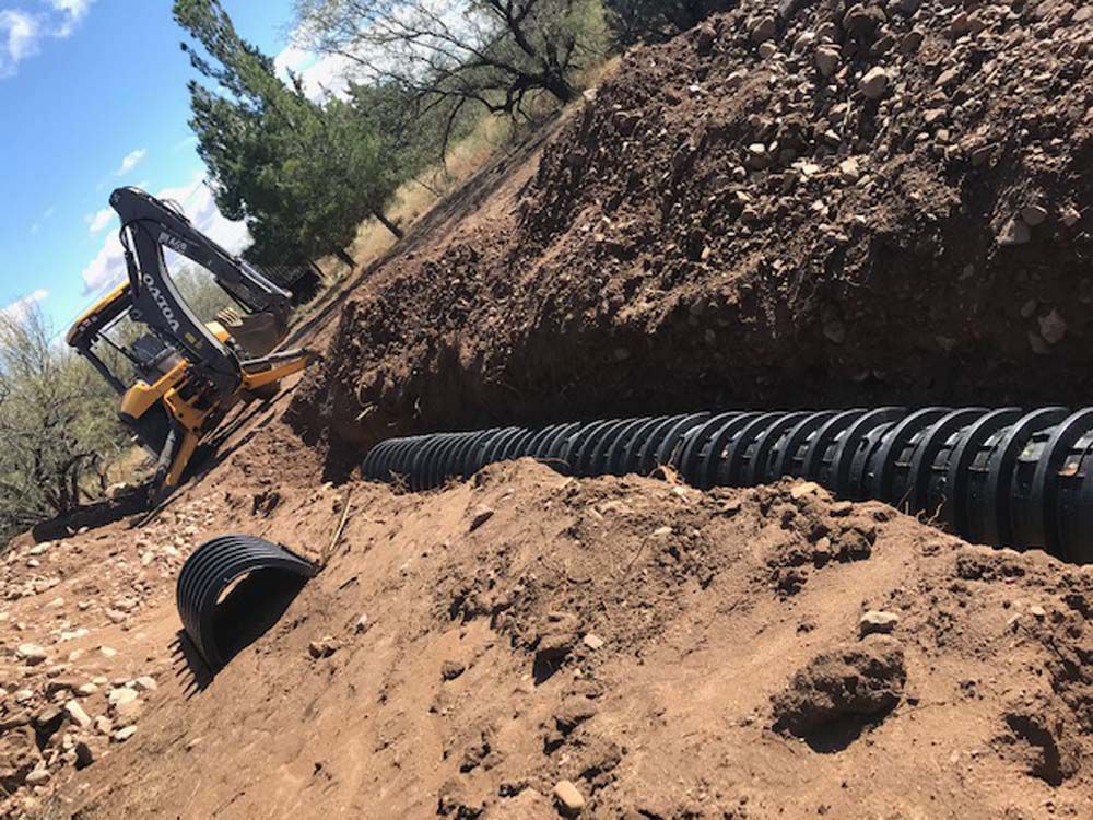 A yellow and black excavator is digging a hole in the dirt