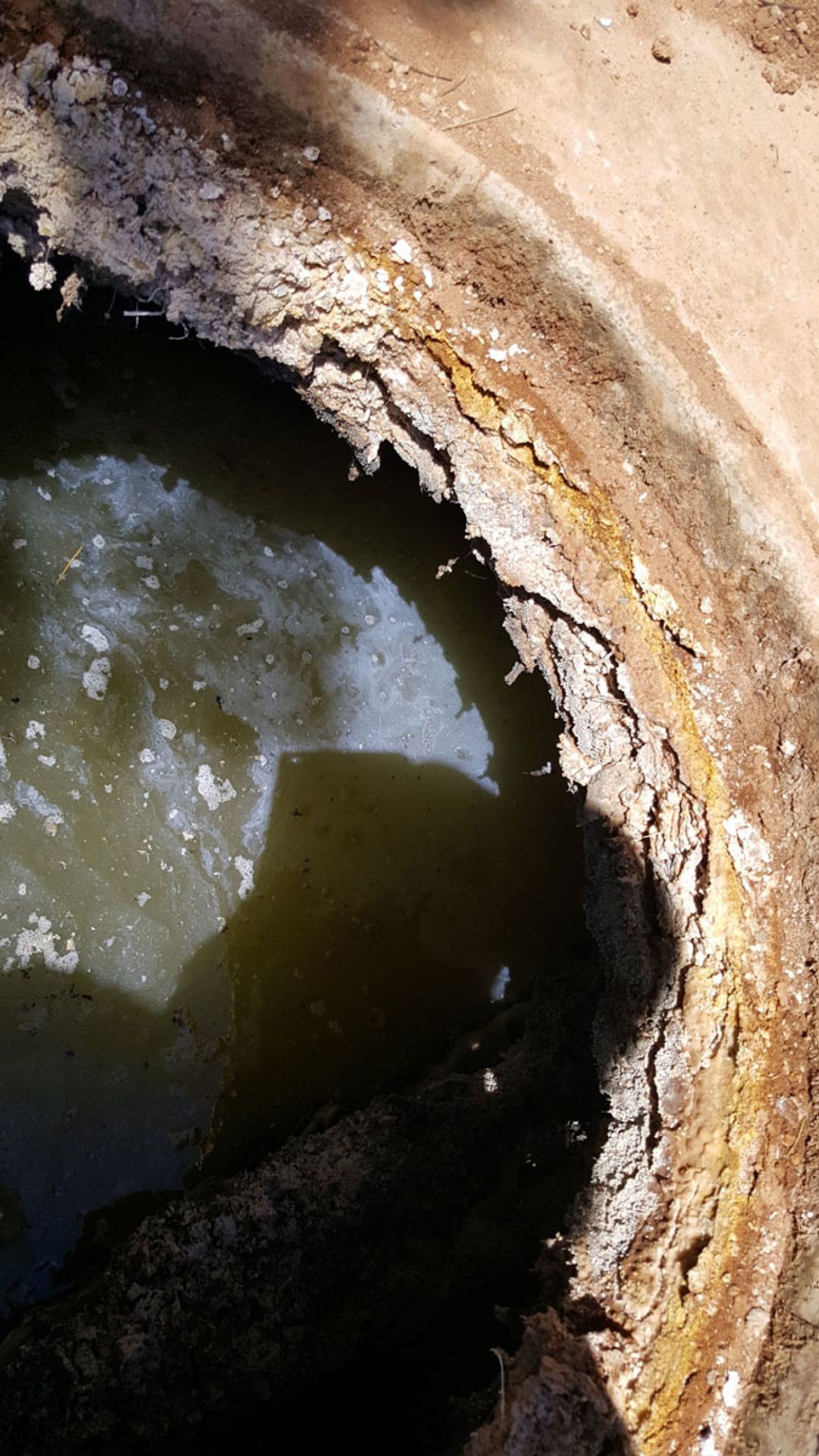 A close up of a hole in the ground with water in it