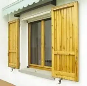 Finestra in legno con persiane aperte. Esterno dell'edificio, soleggiato.