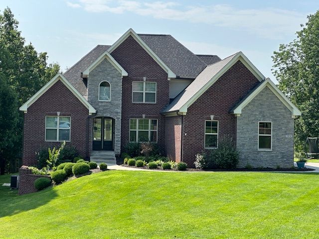A large brick house with a lush green lawn in front of it