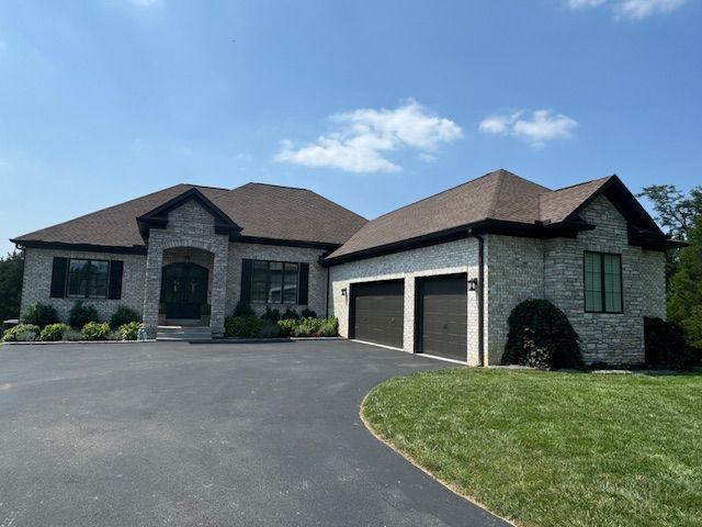 A large brick house with two garage doors and a driveway