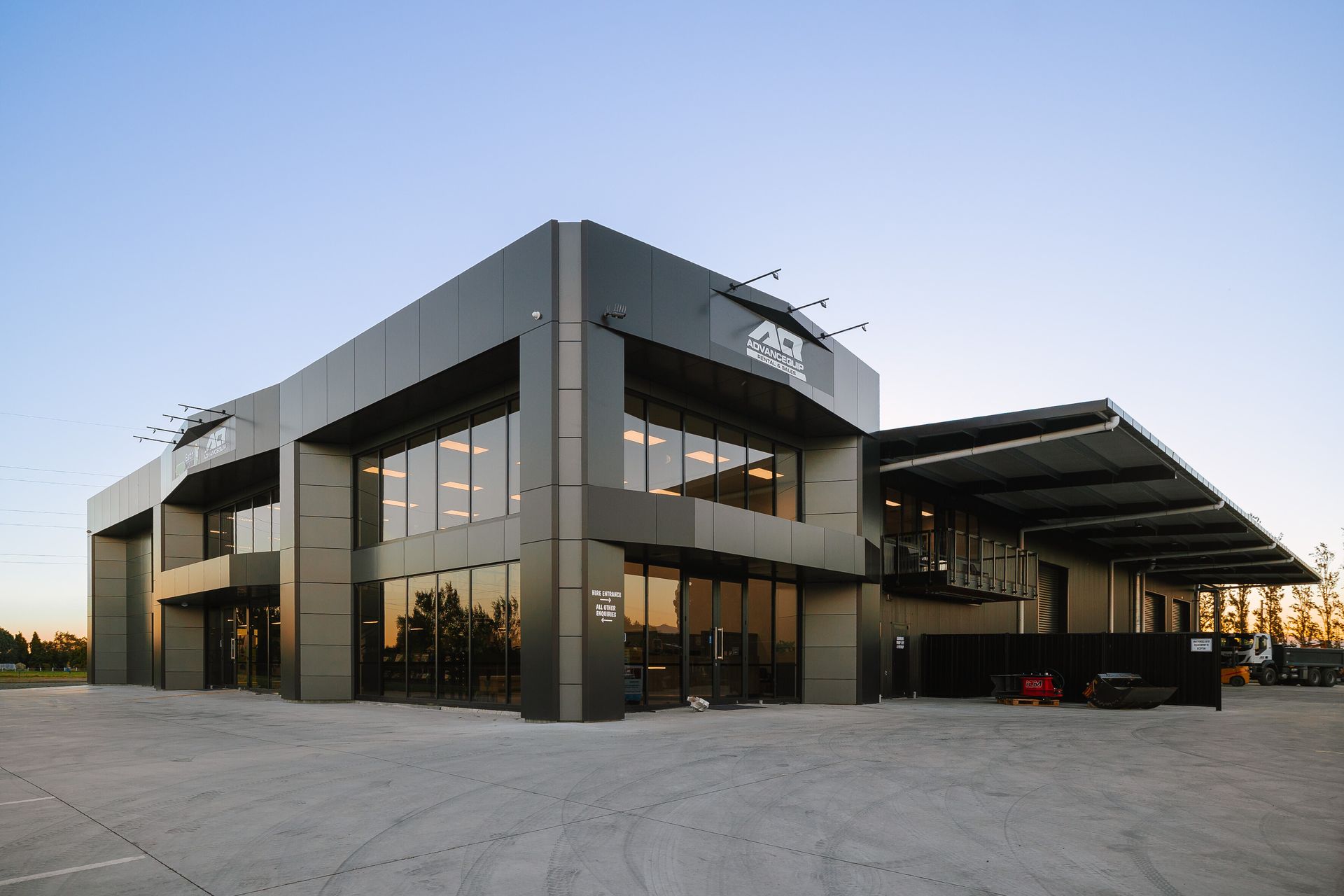 Steel frame of a building under construction against a bright blue sky with wispy clouds.