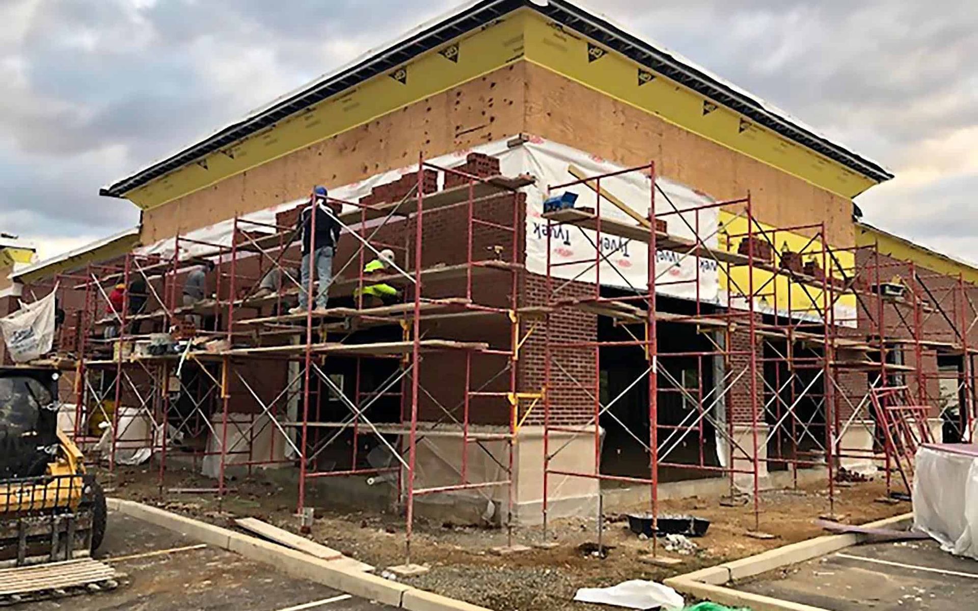 Construction workers discussing plans at a building site, surrounded by lumber and scaffolding.