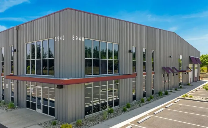 Construction worker in orange vest and hard hat overseeing a concrete truck at a building site.