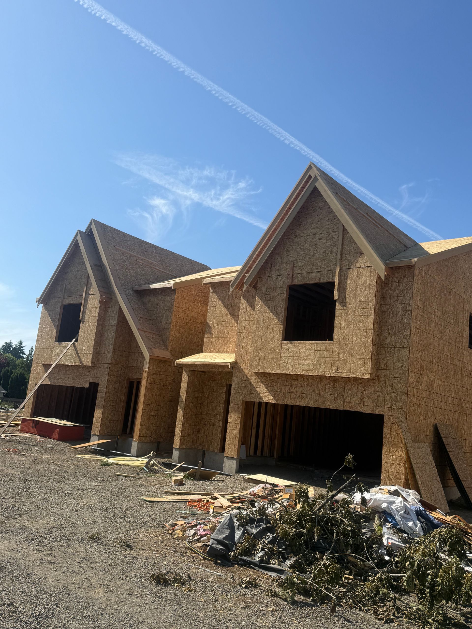 New houses under construction with exposed wooden frames against a blue sky.