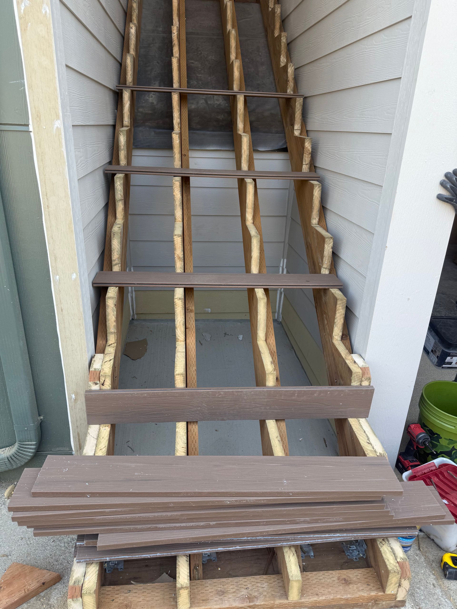 Staircase under construction with exposed wooden frame and composite decking boards.