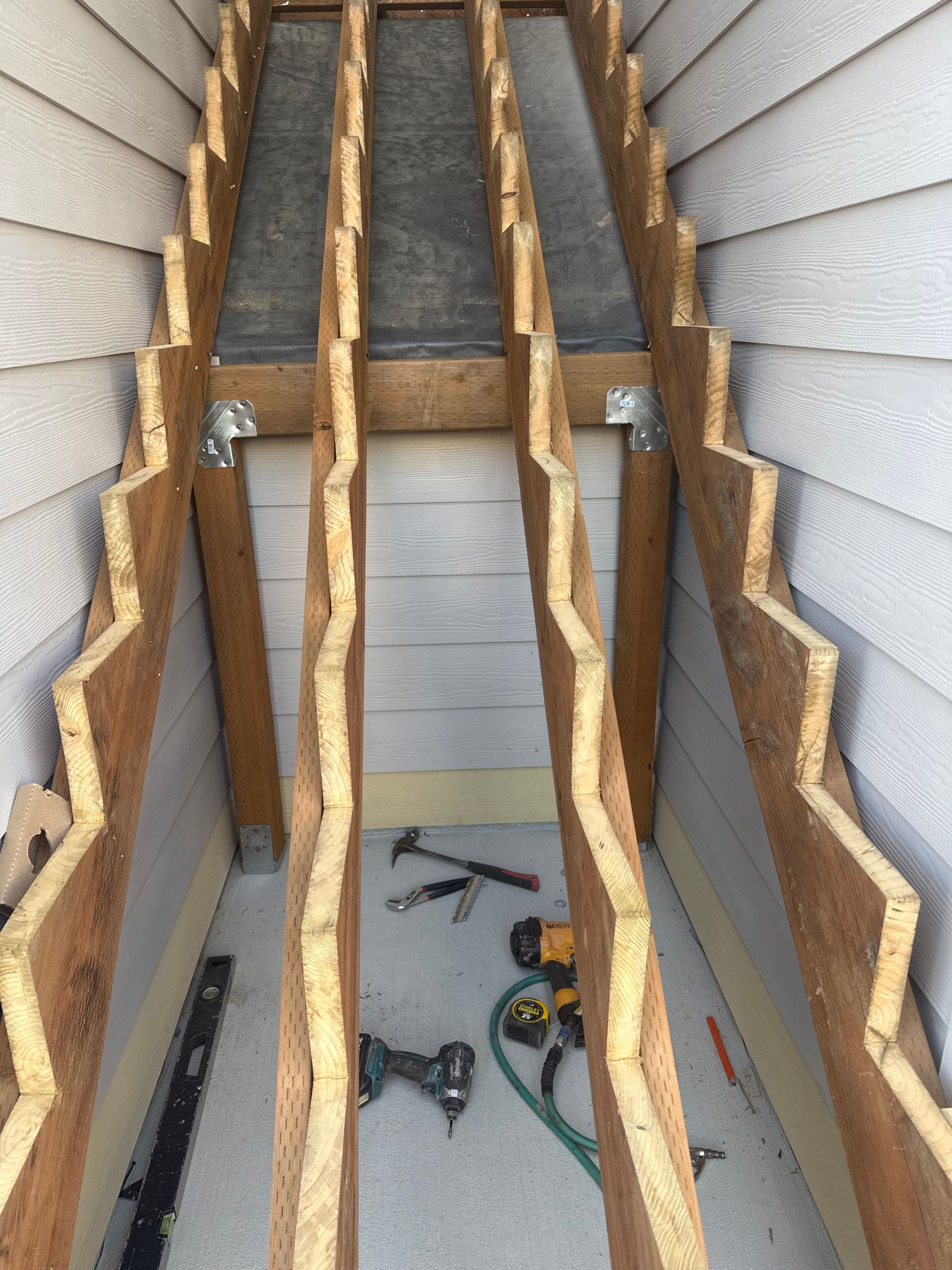 Wooden structure with zigzag edges, construction materials on the floor, between siding.