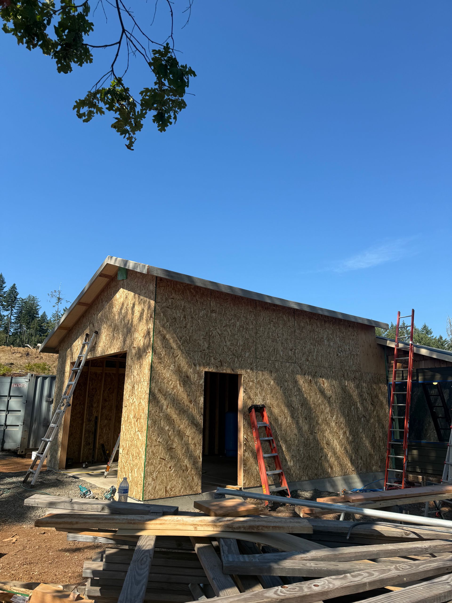 A building under construction with bamboo-like material on the exterior walls against a blue sky.