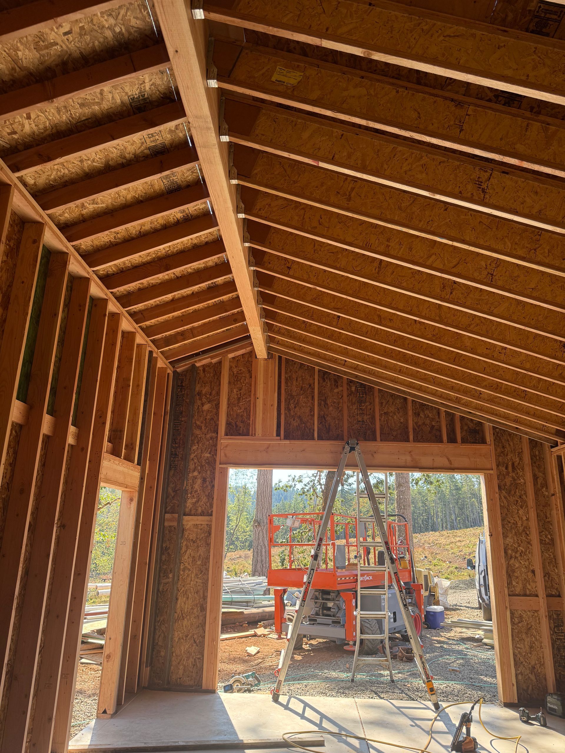 Interior of a building under construction, showing wooden framing, an open doorway, and an orange lift.