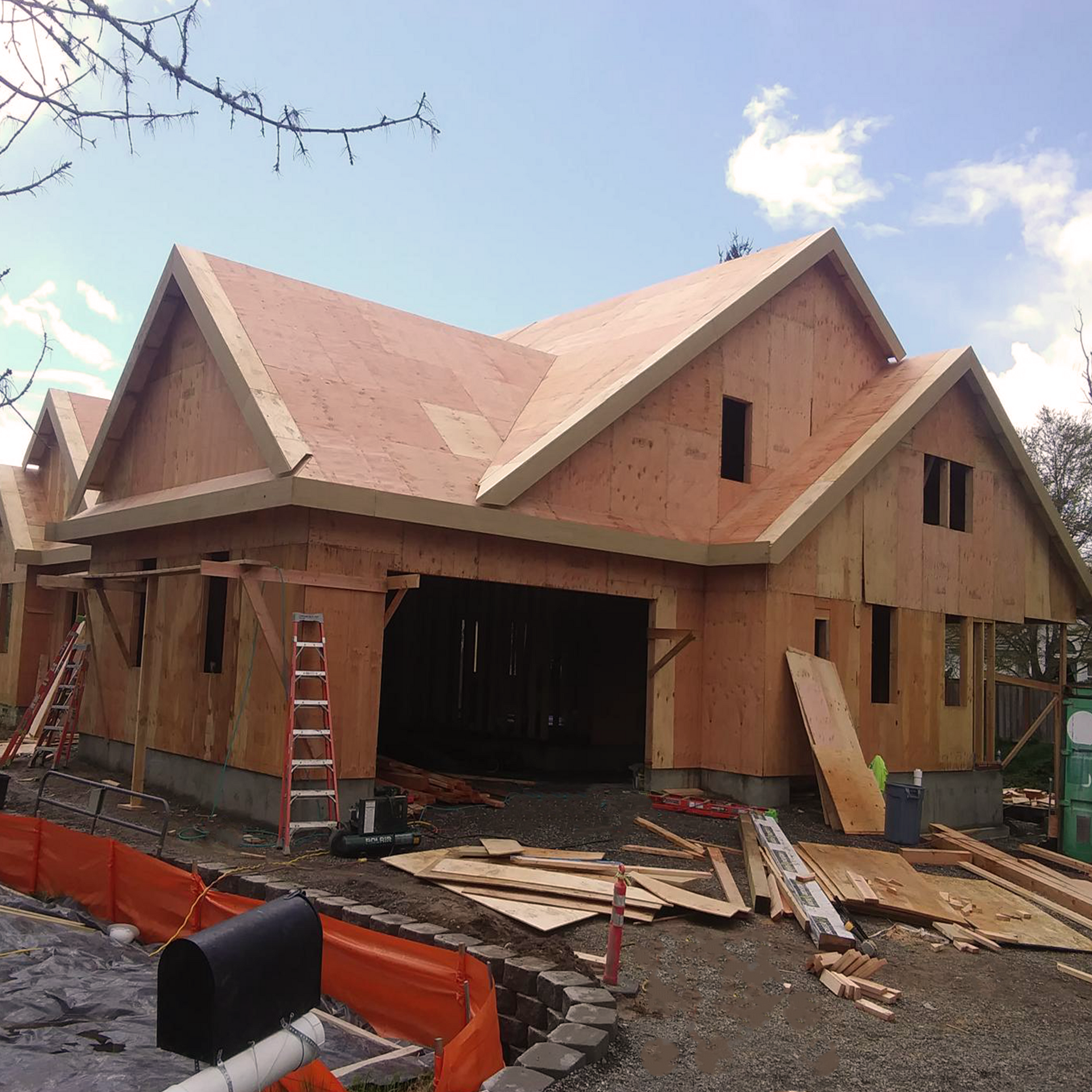 House under construction, unfinished wooden frame with roof, garage, and windows.