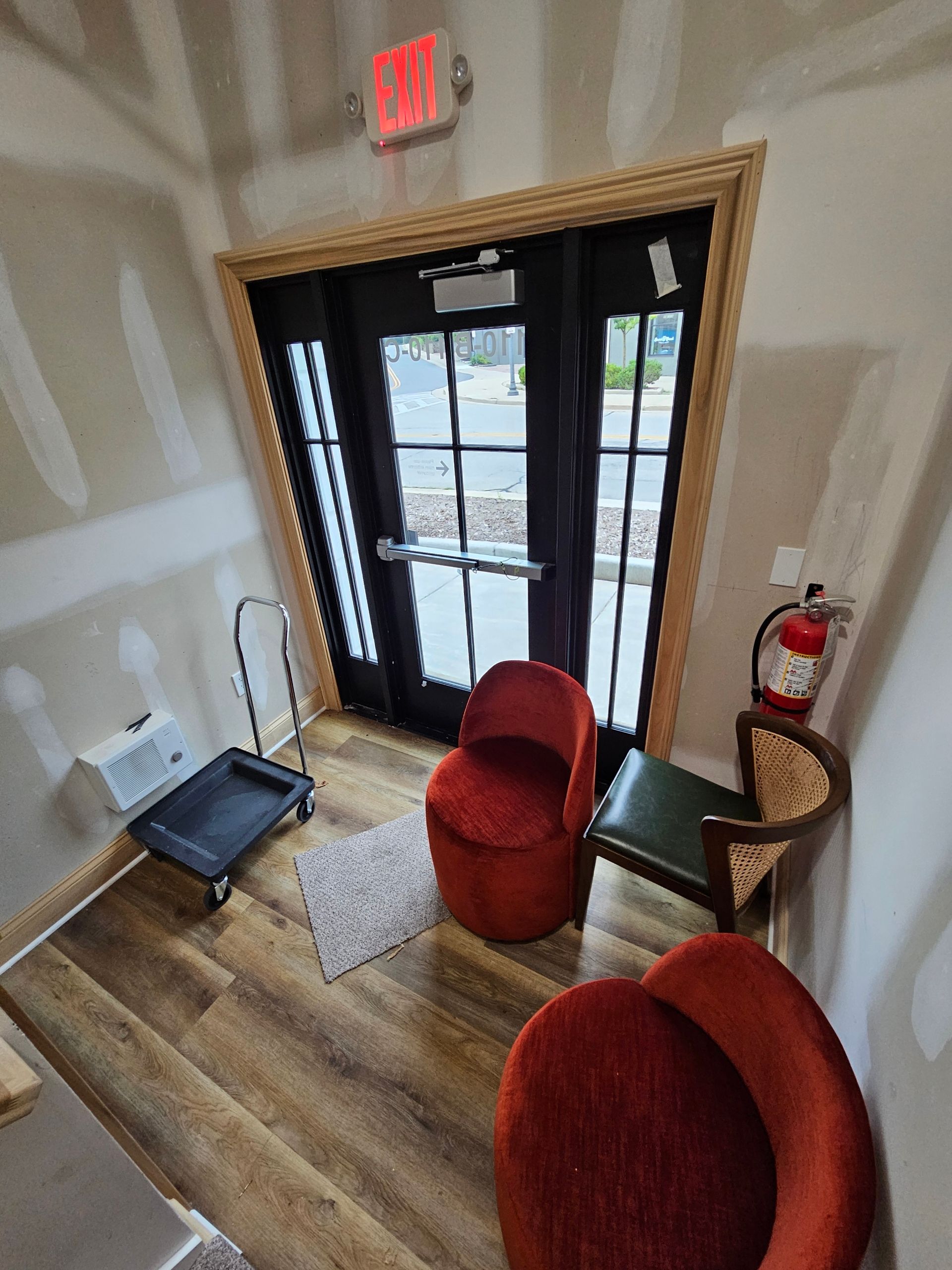 Entryway with black door, red chairs, hand truck, and fire extinguisher.
