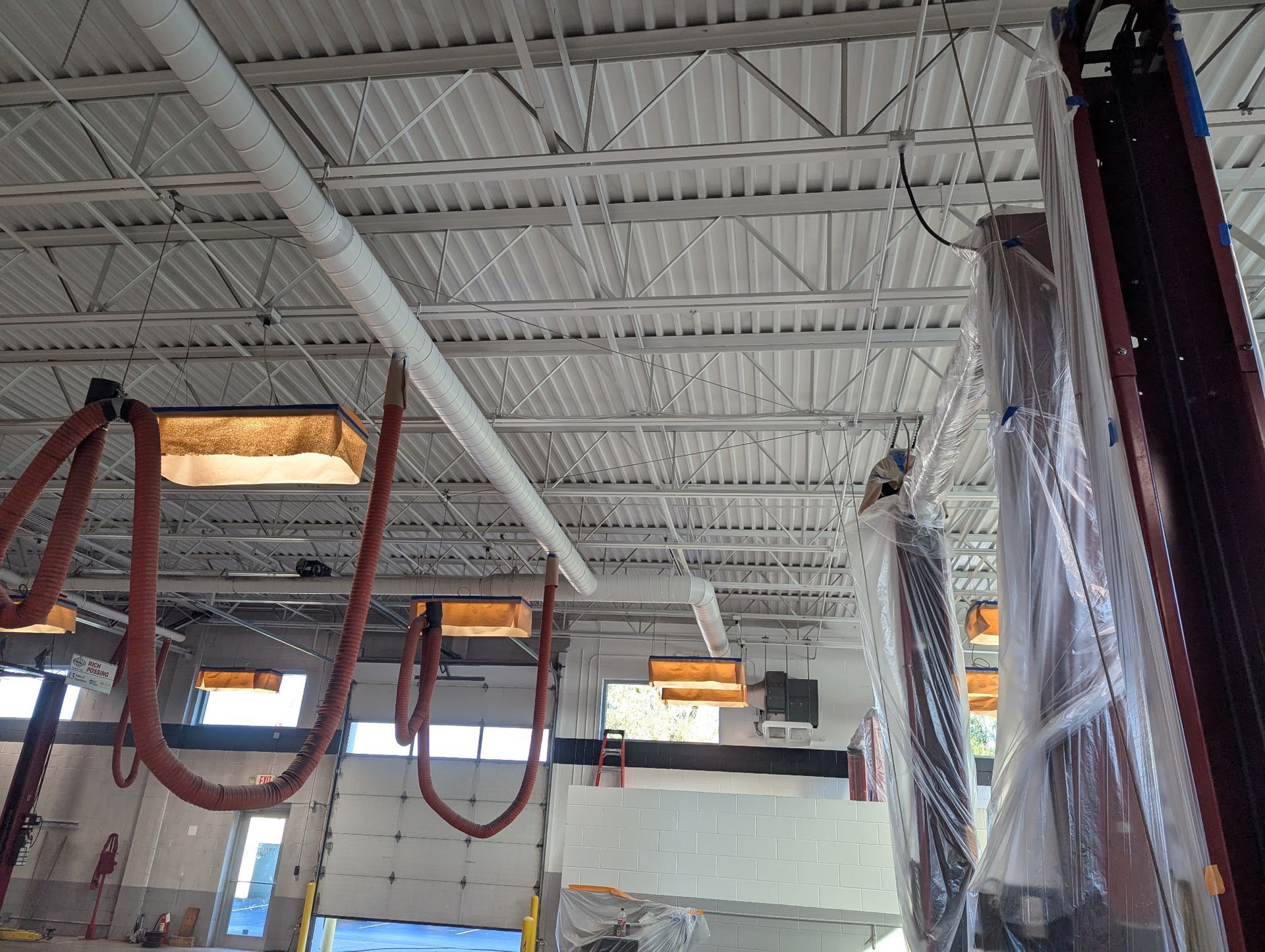 Garage ceiling with white metal supports, ventilation tubes, and covered equipment.