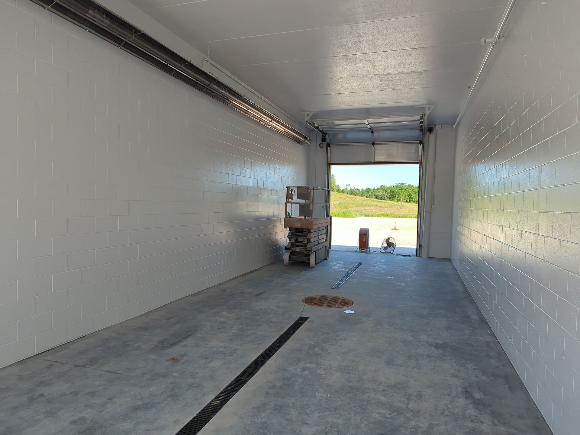 Interior of a white, empty refrigerated trailer with a loading dock at the end.