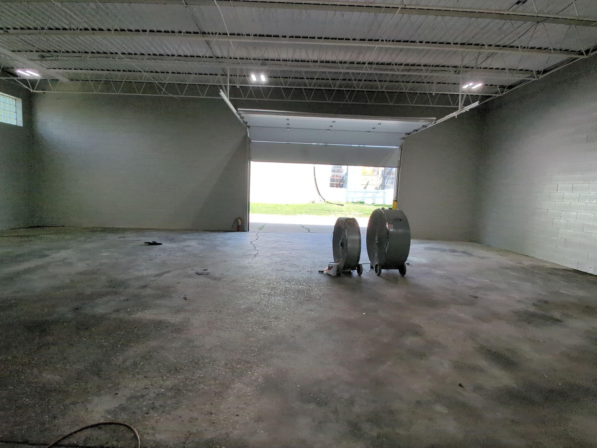 Interior of a concrete room with a large opening, light from outside, two large tanks.