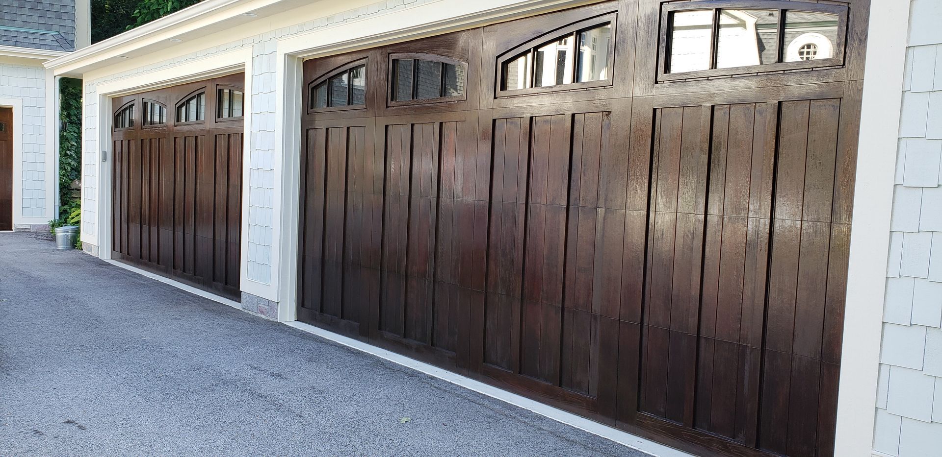 Brown garage doors with arched windows; gravel driveway.