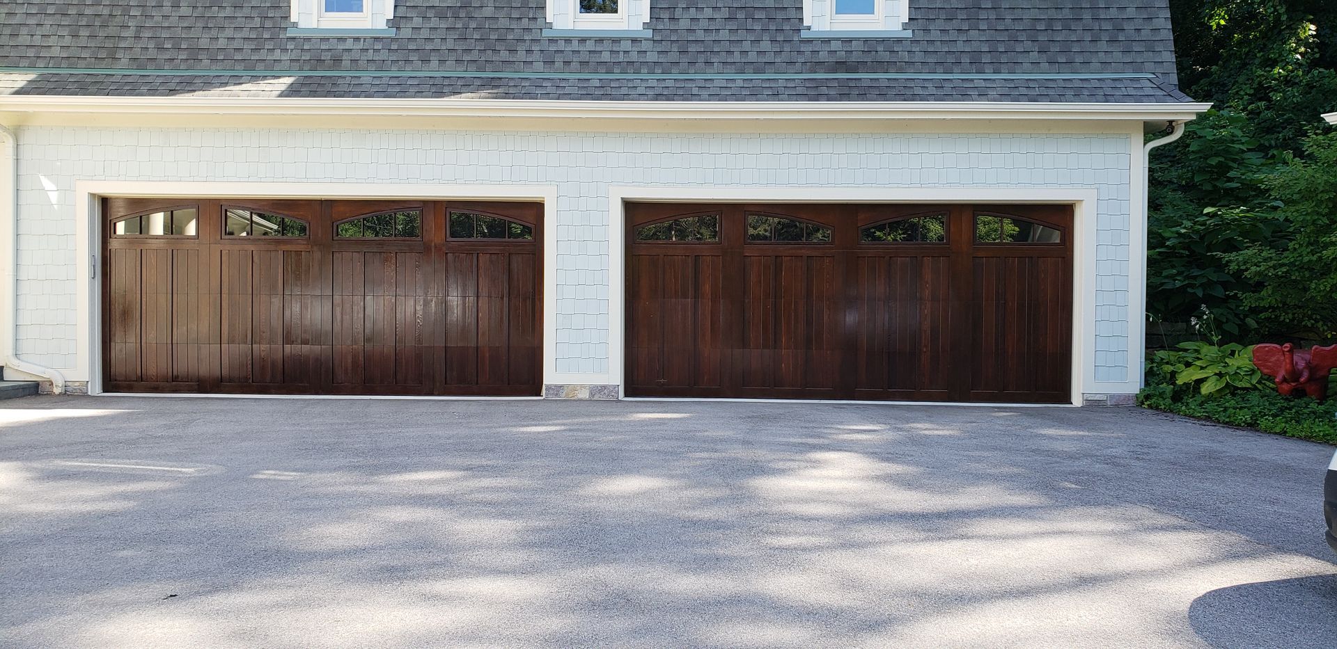 Two-car garage with brown doors and gray gravel driveway.