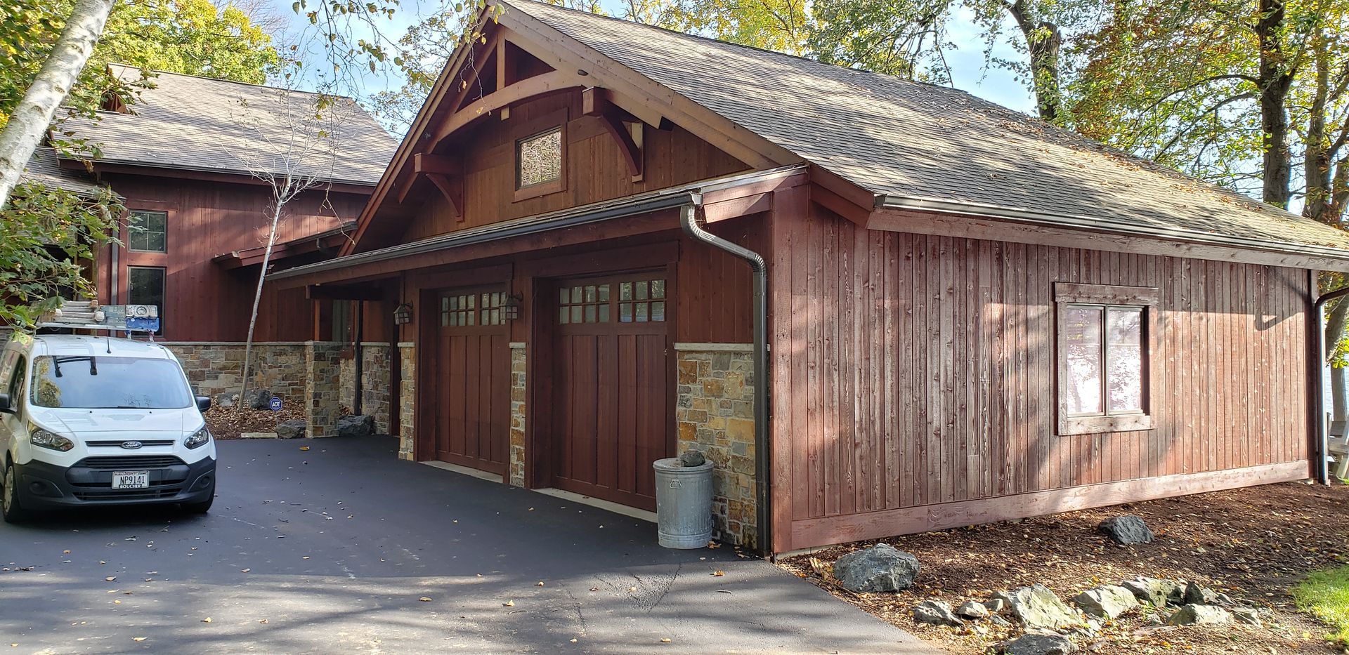 Brown wooden house with a driveway. A white van is parked on the driveway.