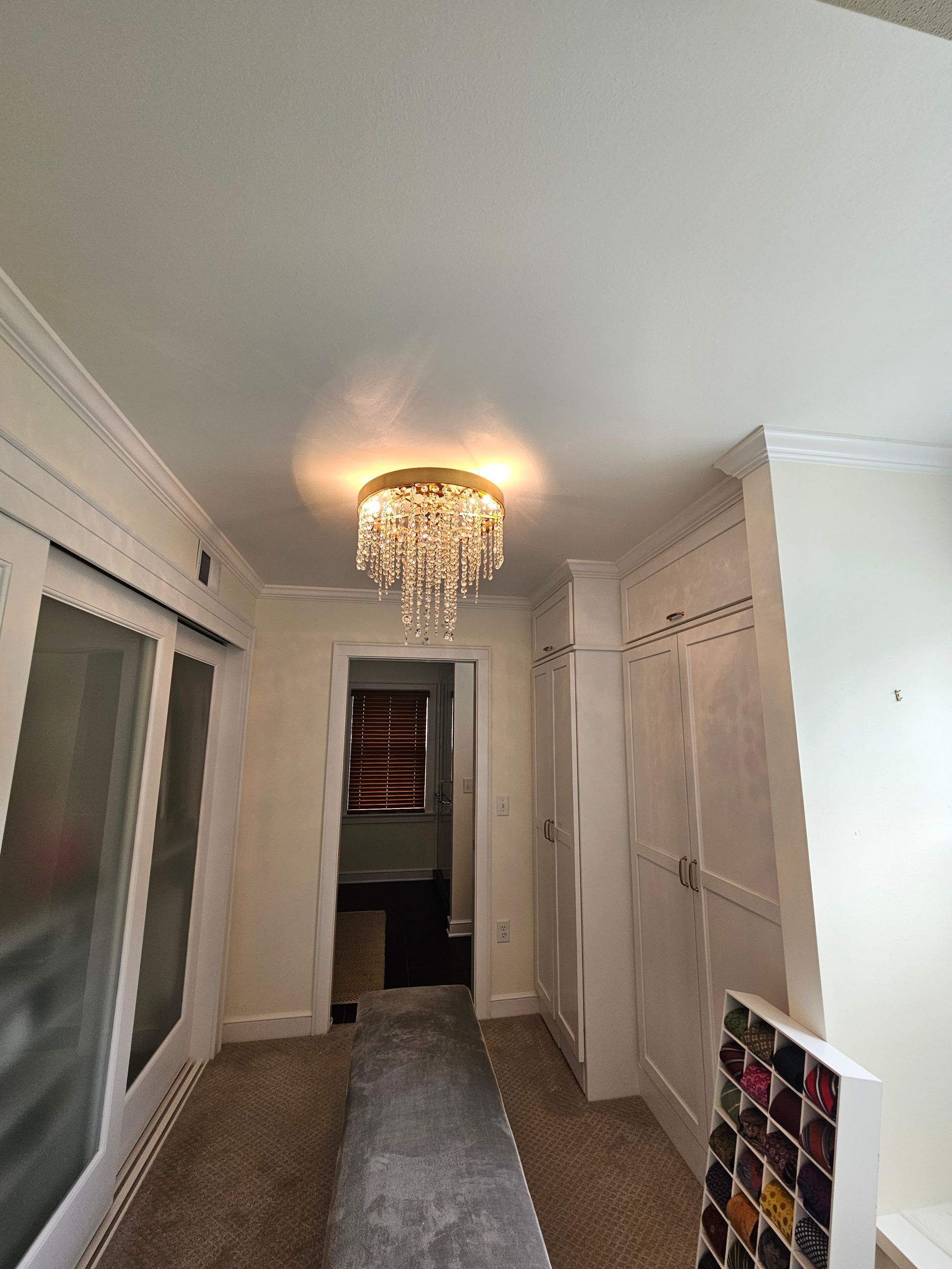 Hallway with white walls, a chandelier, and a closet.