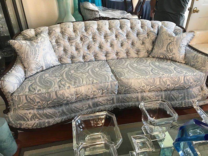 Tufted paisley loveseat with two matching pillows, dark wood frame, glass table.