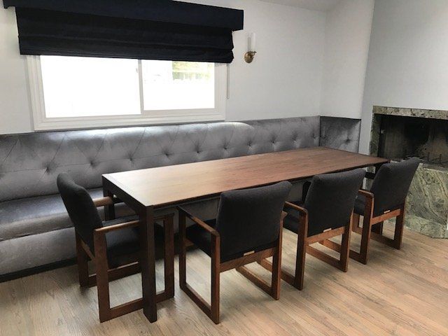 Dining room with long wooden table, built-in gray cushioned bench, and four dark armchairs.