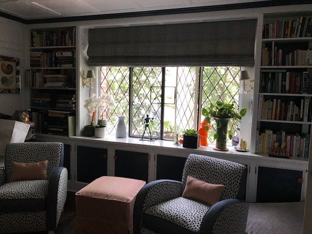 Cozy reading nook with bookshelves, a window with latticework, two armchairs, and an ottoman.