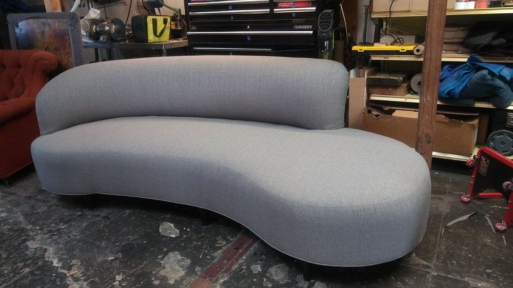 Gray curved sofa in a workshop setting.
