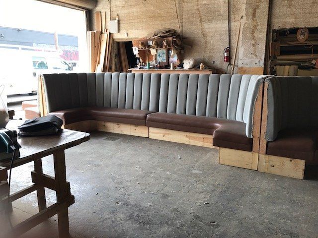 A large, grey and brown booth with vertical ribbed backing in a workshop setting.