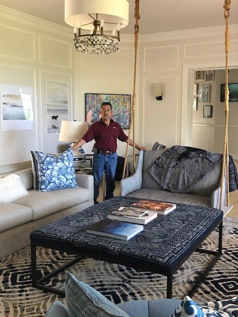 Man standing in a living room with a blue and white color scheme, large ottoman, and swing.