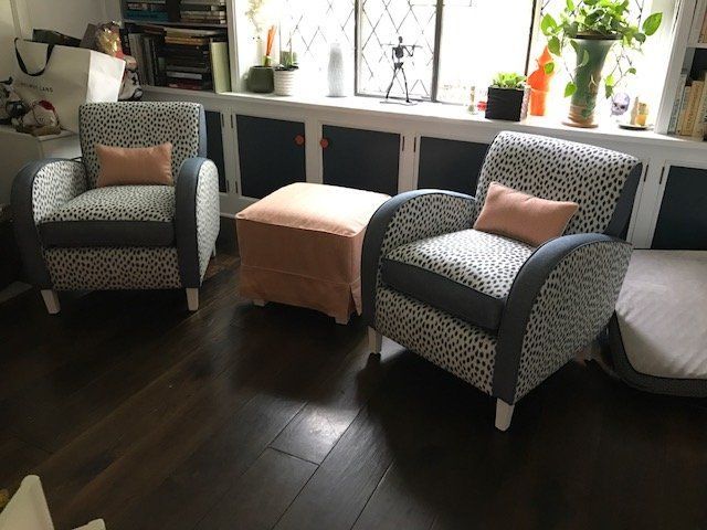 Two patterned armchairs with a matching ottoman, in front of a window.