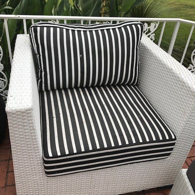 White wicker chair with black and white striped cushions on a patio.