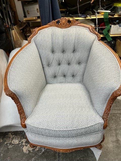 Upholstered armchair with light gray patterned fabric and ornate wooden frame.
