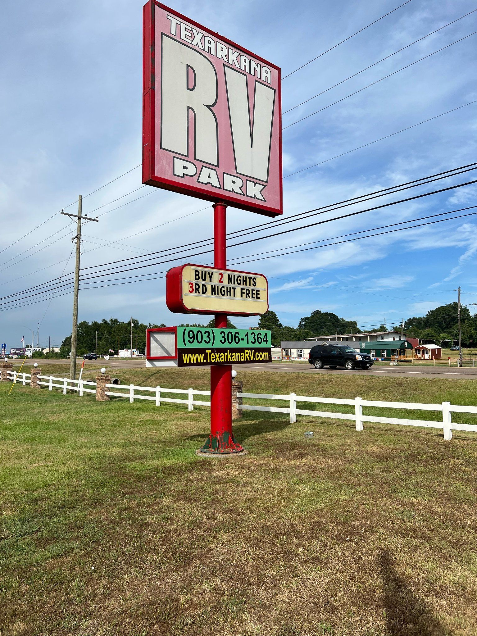 A large red sign with the word on it is in the middle of a grassy field.