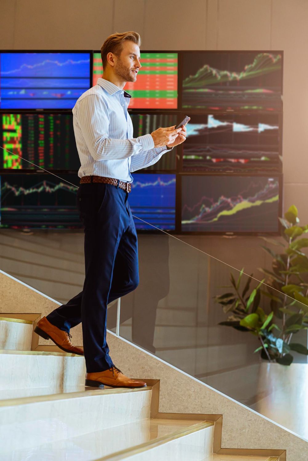 A man is walking up a set of stairs while looking at his phone.