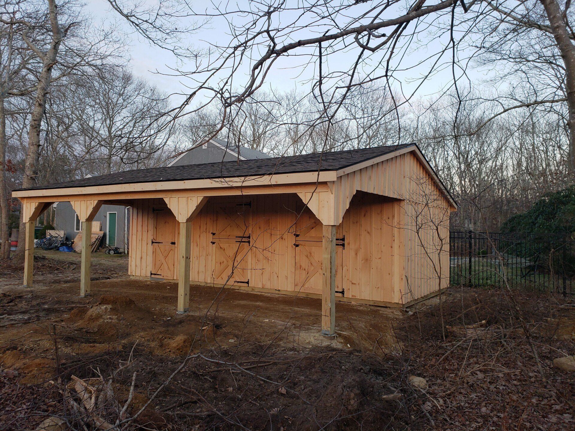 A wooden shed with a roof is sitting in the middle of a forest.