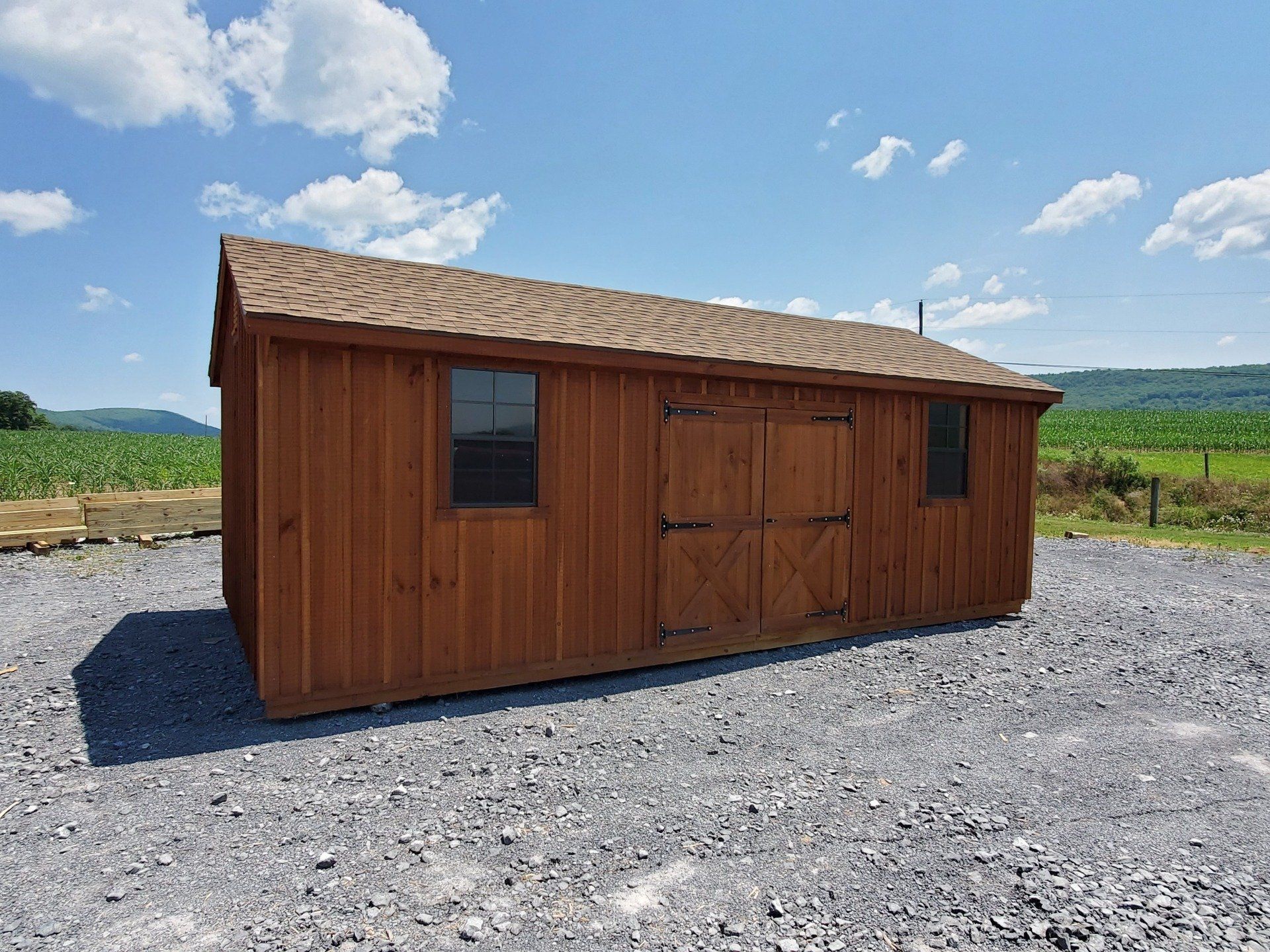 A wooden shed is sitting on top of a gravel lot.