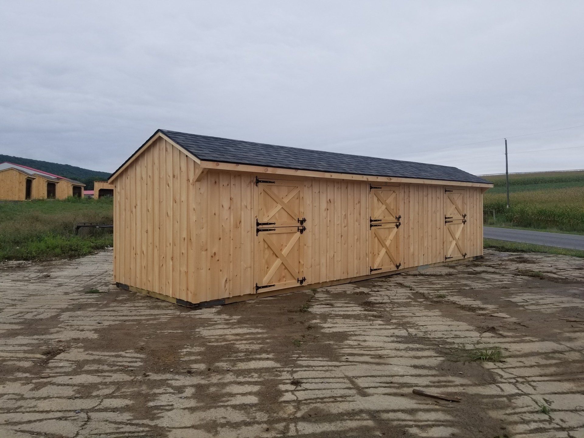 A wooden shed is sitting in the middle of a dirt field.
