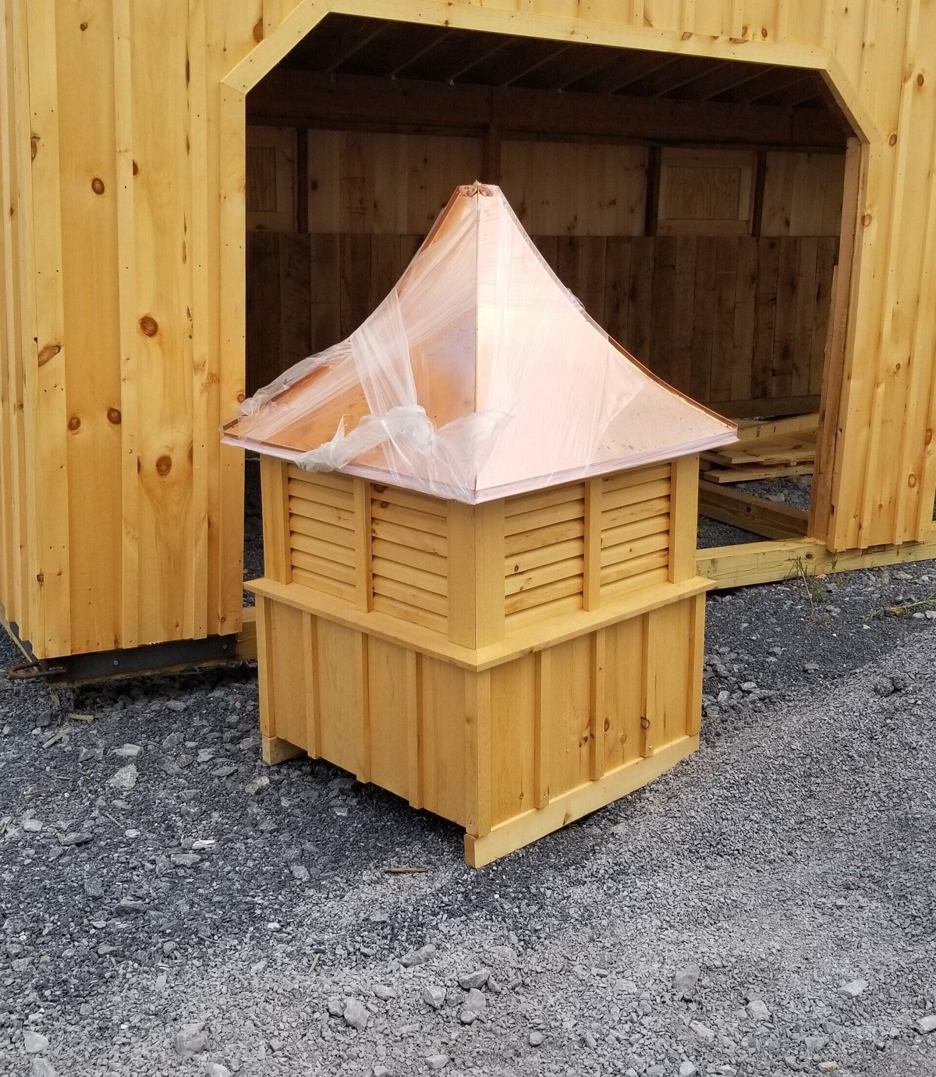 A wooden structure with a copper roof sits in front of a wooden building