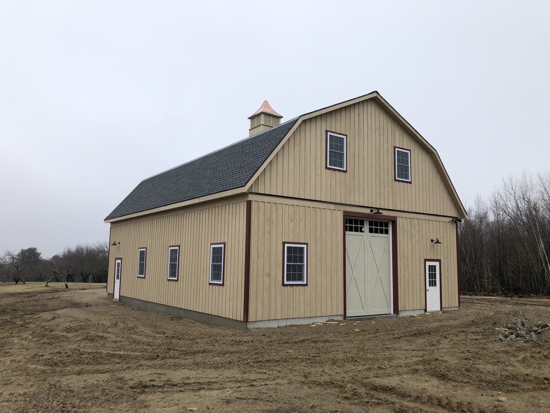 A large barn is sitting in the middle of a dirt field.