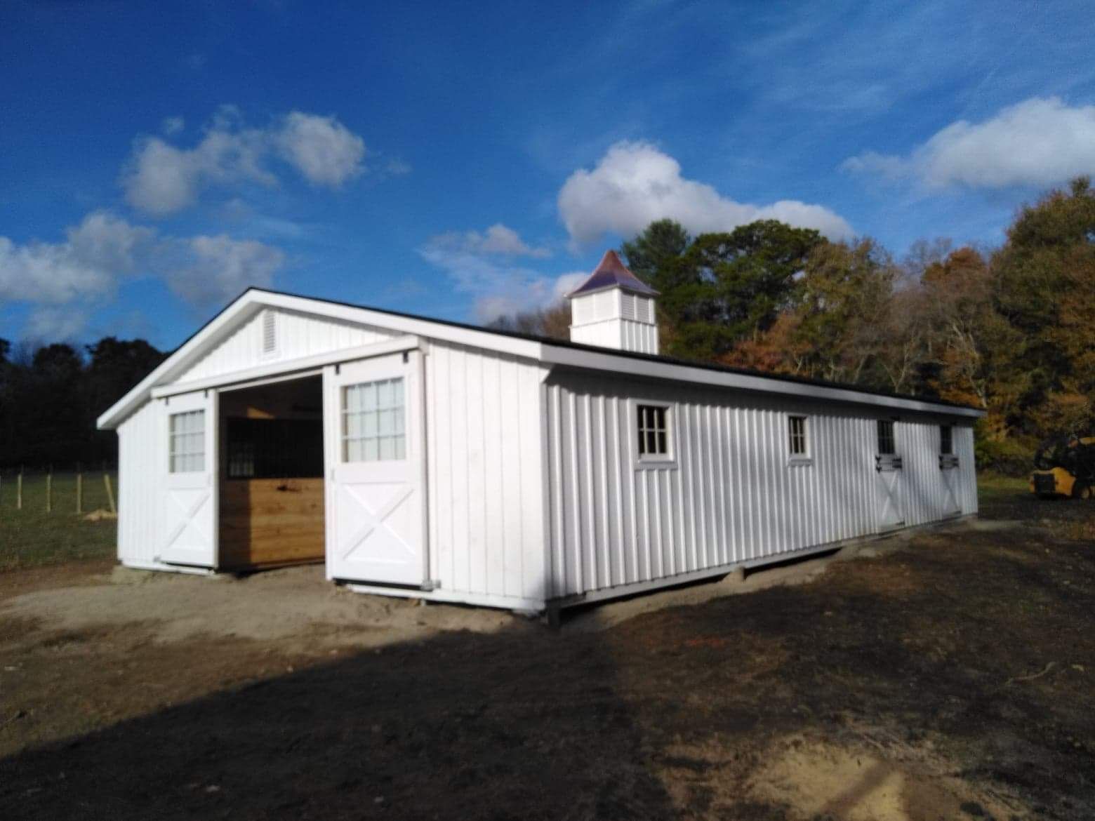 A white barn with a chimney on top of it