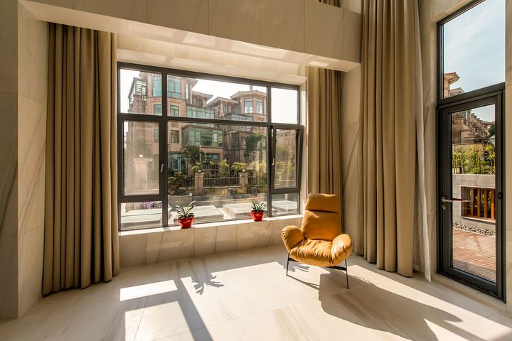 A living room with a yellow chair and a large window.