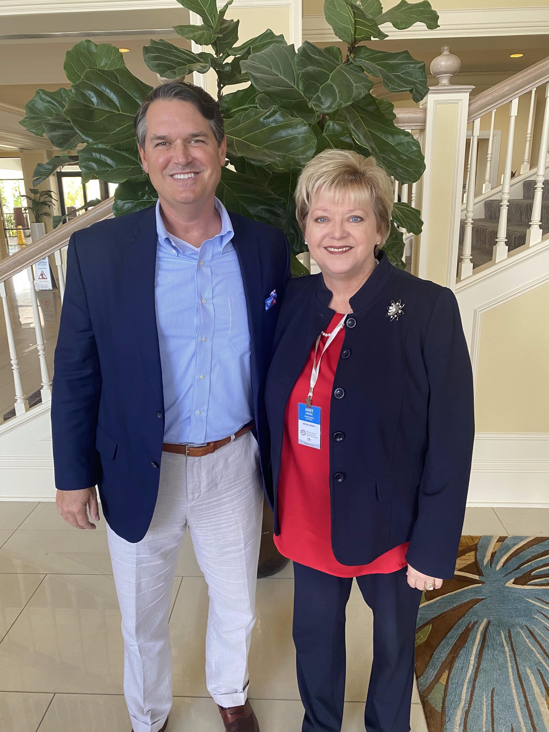 A man and a woman are posing for a picture in front of a plant.