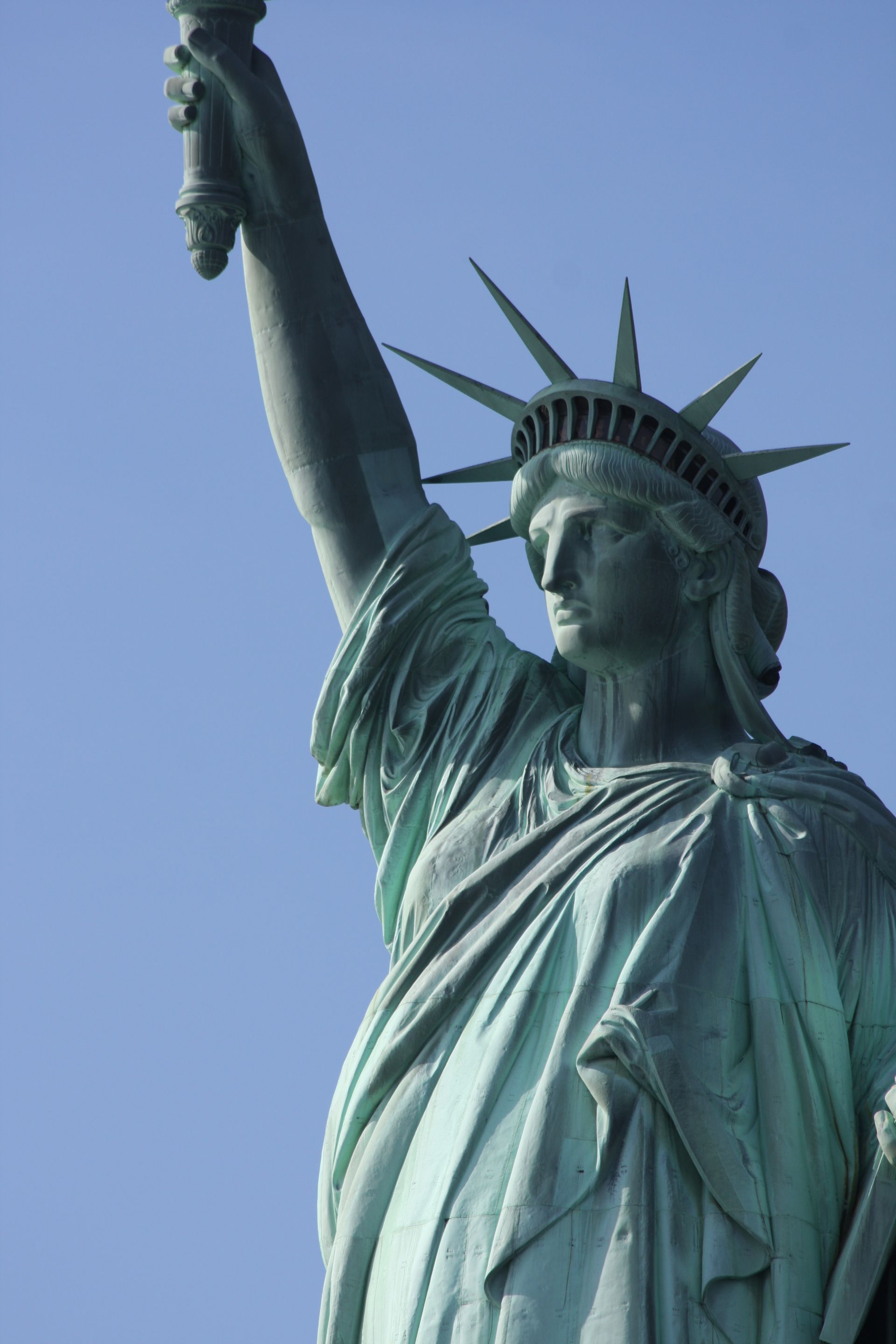 The statue of liberty is holding a torch in front of a blue sky