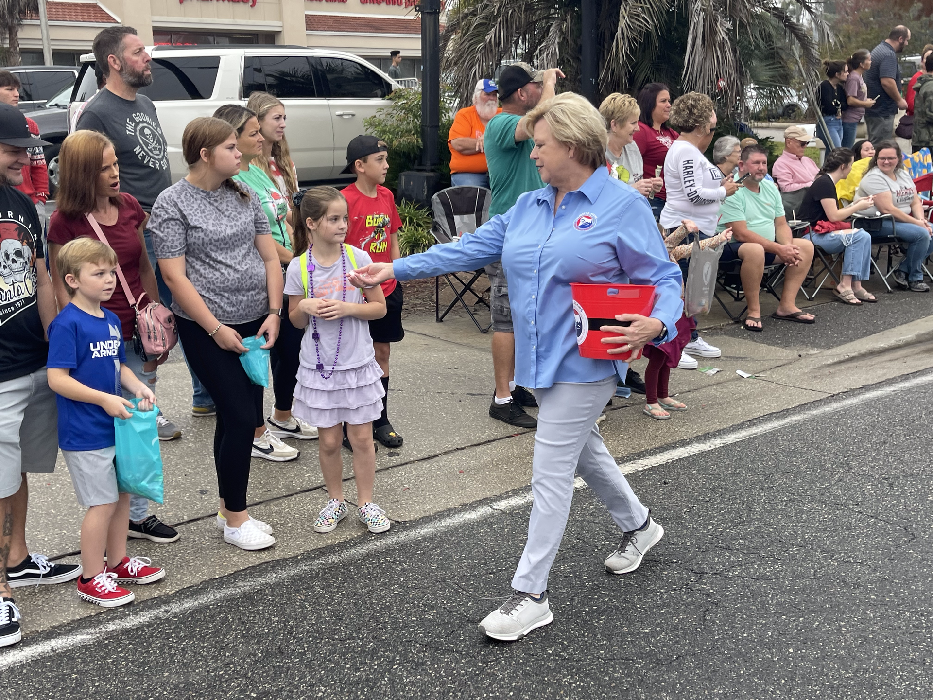 A woman is walking down the street in front of a crowd of people.