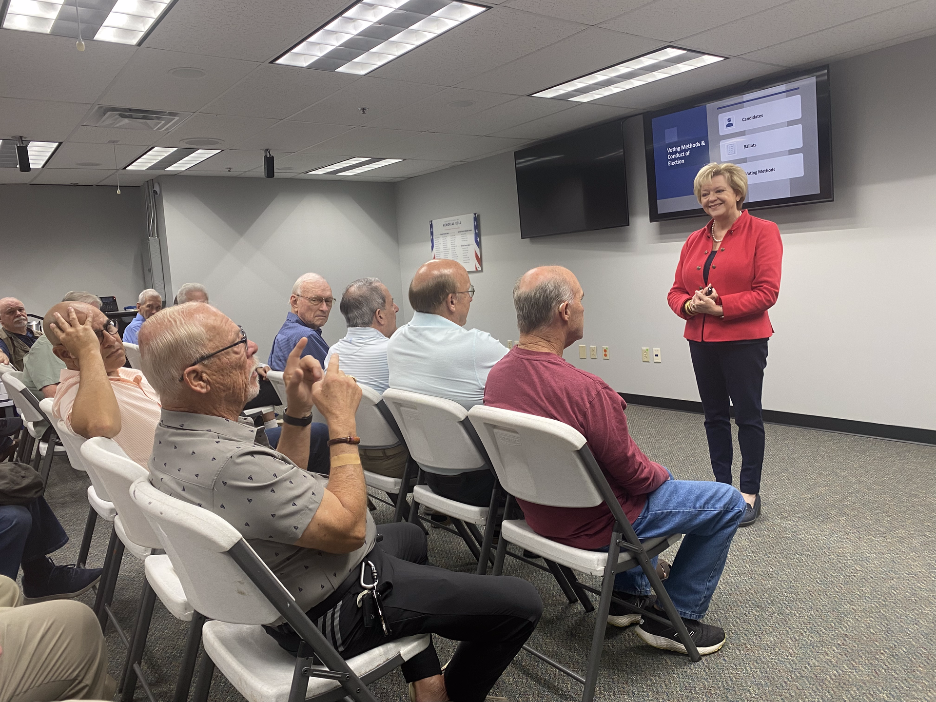 A woman is giving a presentation to a group of people sitting in chairs.