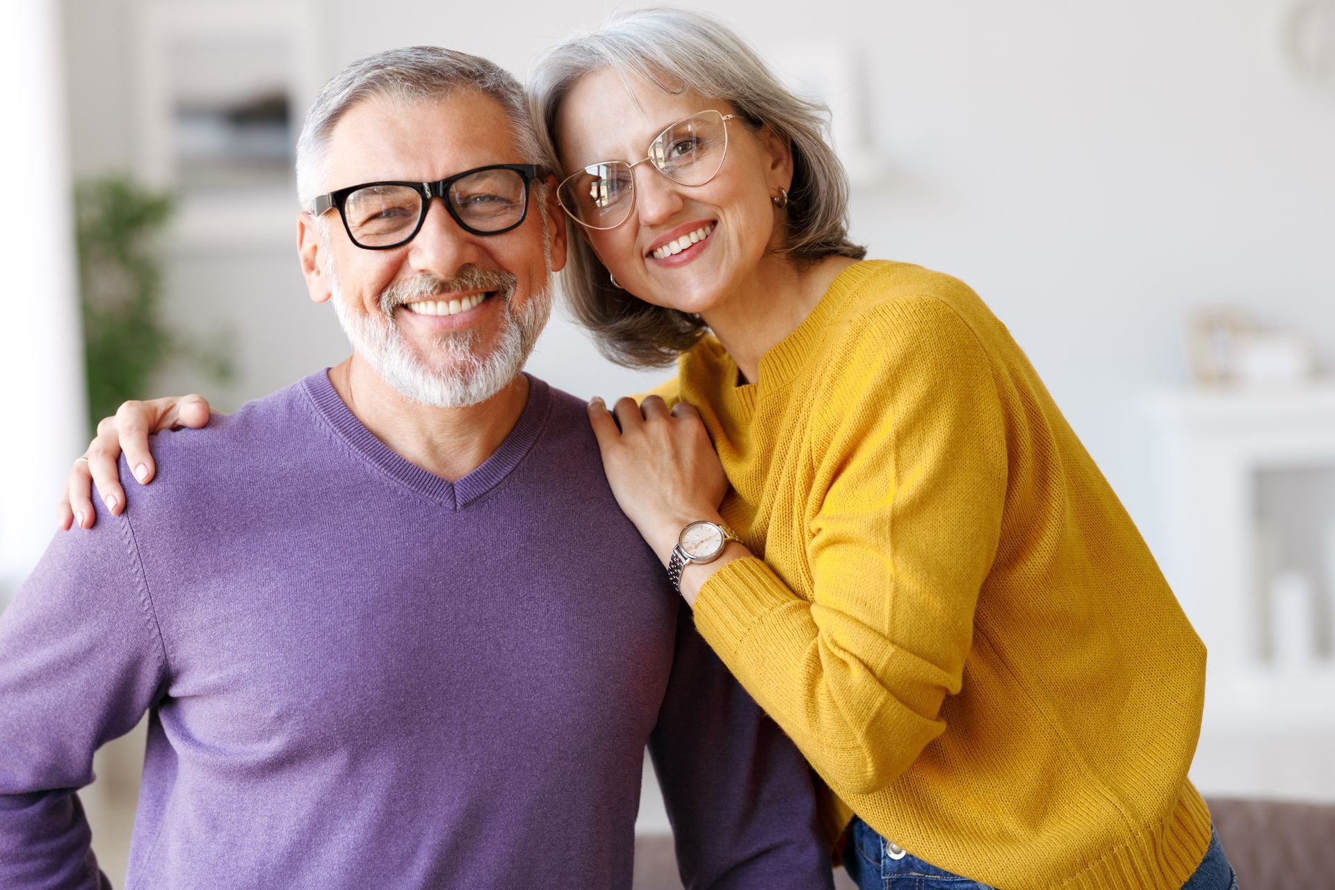 Older couple smiling after dental implant treatment