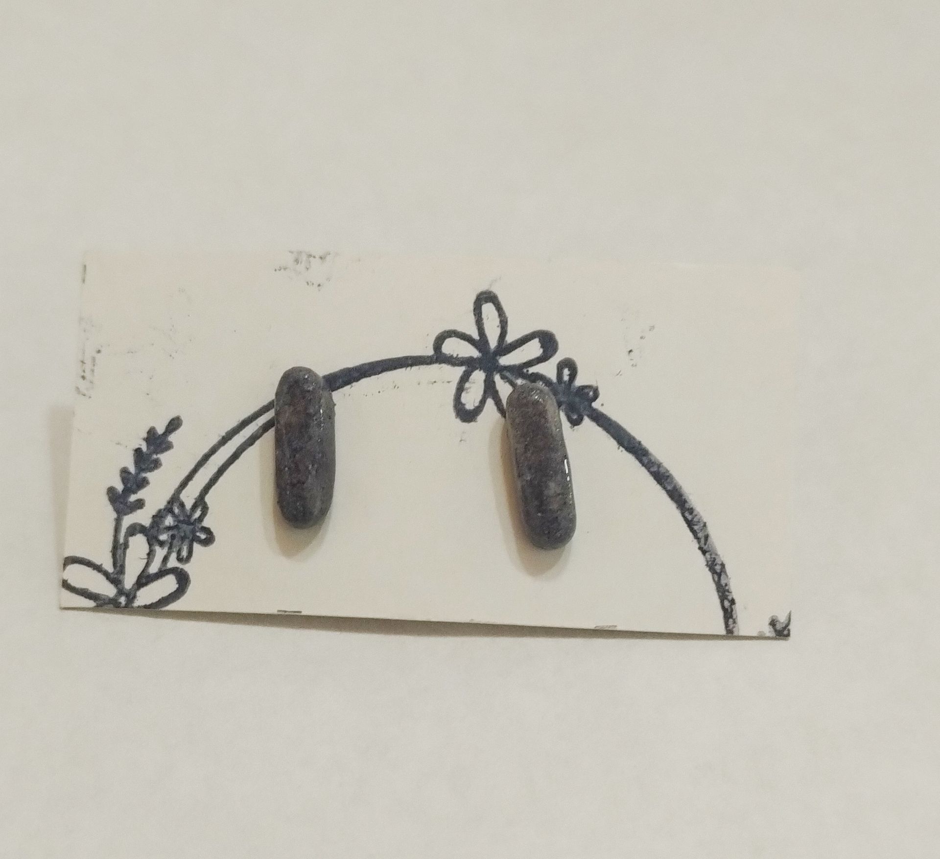 Un par de pendientes en una tarjeta con un diseño de flores.