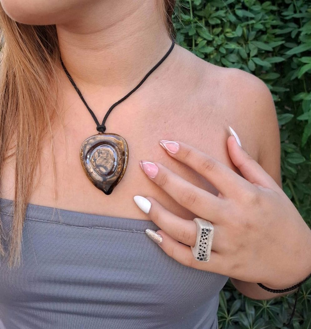 Una mujer que lleva un collar y un anillo en el dedo.